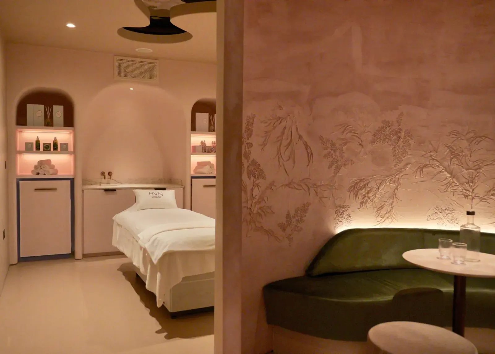 HVN Knightsbridge treatment room and green banquette by SheridanCX against a botanical bas-relief wall in warm light