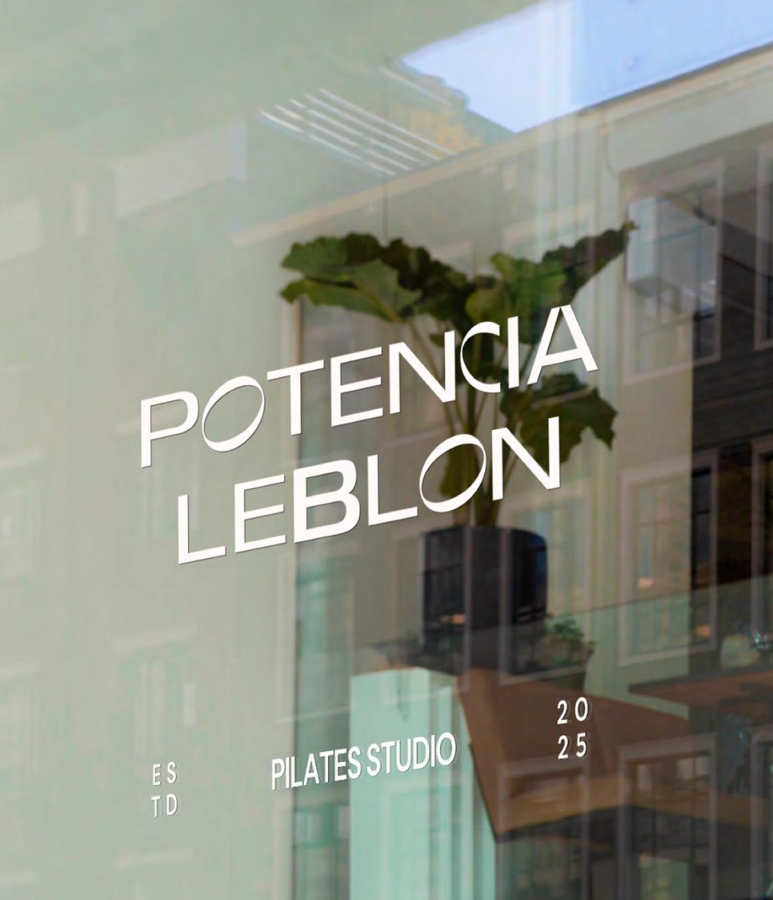 Potência Leblon Pilates Studio storefront window with vinyl signage and street reflection
